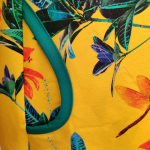 Gul plus size kjole i a-form med v-hals. Kjolen har blomster og guldsmede.