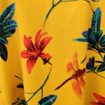 Gul plus size kjole i a-form med v-hals. Kjolen har blomster og guldsmede.