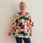 Sakura Bluse - Bauhouse. A-formet bluse fra Amamiko med markant geometrisk print i rød, gul og blå på en klassisk hvid baggrund
