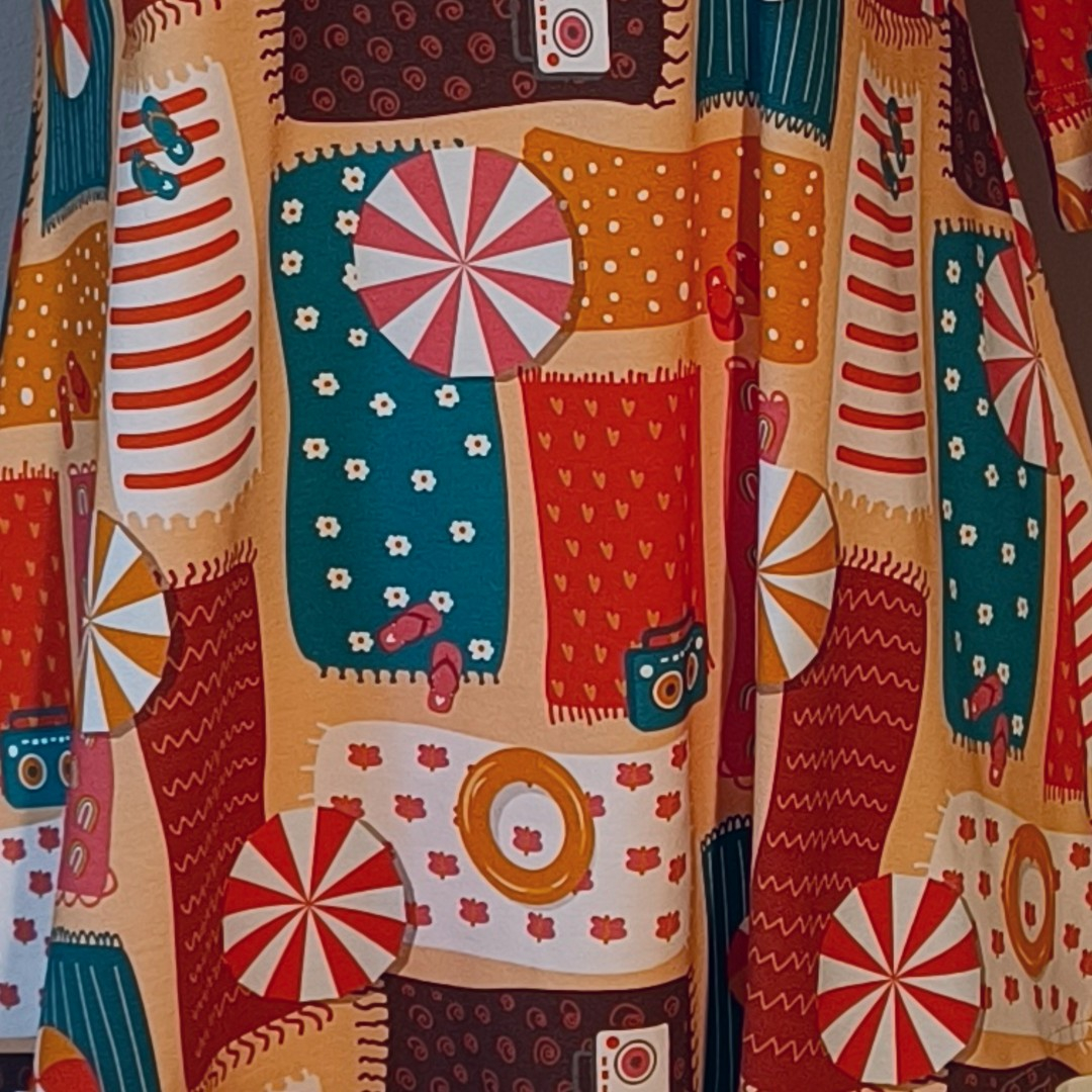 Sakura Beach Relaxation. A-formet bluse fra Amamiko med print af strandhåndklæder, baderinge og parasoller i varme, ferie-agtige farver