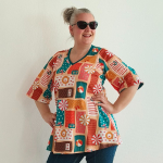 Sakura Beach Relaxation. A-formet bluse fra Amamiko med print af strandhåndklæder, baderinge og parasoller i varme, ferie-agtige farver